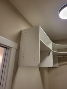 Painted shelving unit with adjustable shelf pin holes and a chrome hanging rod installed