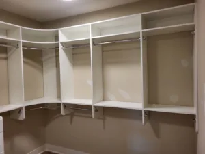 Closet system with painted white shelves, chrome hanging rods, and dividers in a walk-in closet