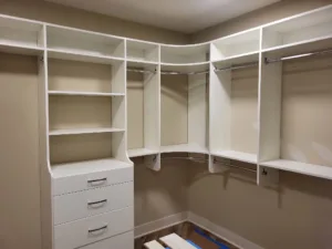 Corner closet shelving with a curved overhead rod, open shelves, and a drawer unit on both walls