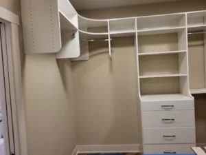 Closet shelving with a curved overhead rod, open shelves, and a drawer unit, painted walls