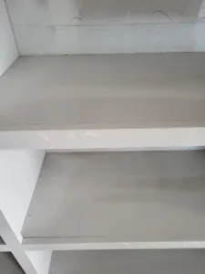 Primed shelf corner with a textured painted finish, exposed wire visible near the ceiling