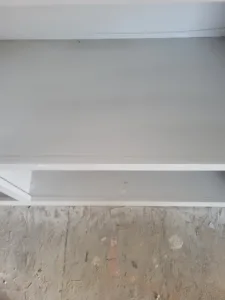 White painted floating shelves stacked above a rough OSB subfloor, viewed from below.