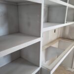 Custom built-in bookcase with white face-frame shelving and open compartments under construction.