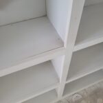 Custom built-in bookcase with multiple shelves and dividers, raw wood ready for paint.