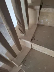 Paper wrapped balusters and a mitered trim joint at a stair corner, protected during construction