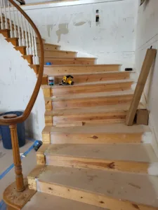 Curved staircase with unfinished wood treads in the foreground and finished balusters above