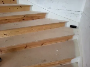 Raw wood stair treads installed along a straight run, ready for stain