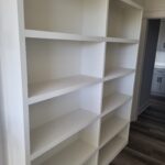 Custom built-in bookcase with painted white shelving and face frame, multiple compartments ready for storage.