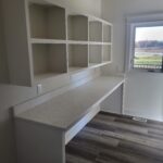 Custom built-in desk with overhead cubby shelving unit, painted white with marble countertop.