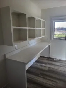 Finished built in closet desk with a white countertop and overhead cubby shelving, window above