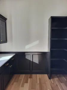 Finished space with painted dark cabinetry, open shelving, and hardwood flooring