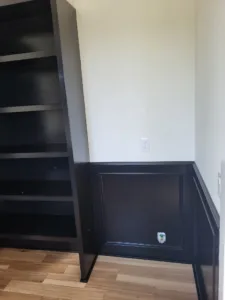 Dark painted wainscoting with frame detail on the lower wall above a hardwood floor