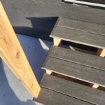 Composite deck steps with closed risers and wood skirt board installed; multiple treads visible with support stringers.