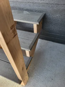 Closeup of closed stair risers, gray stained, set against a natural wood skirt board