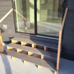 Three-stringer patio steps with open risers and yellow safety tape on treads during construction.