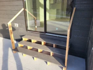Patio steps with three open treads up to a sliding door, a wood rail on each open side