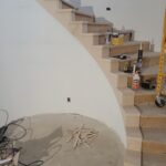 Finished wood risers and treads installed on curved staircase, raw wood ready for paint or stain.
