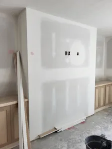 Drywall panel with electrical outlet cutouts, being installed during interior construction