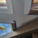 Finished wood window sill/stool installed at interior window opening with protective tape applied.