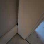 Painted baseboard installed at floor level in corner with door casing detail visible.