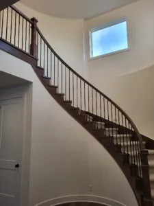 Curved interior staircase with a dark wood skirt board and black metal baluster railing
