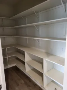 Walk-in closet shelving with face-frame tiers, white brackets, and built-in cubby storage boxes below.