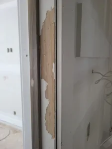 Incorrect: white jamb strip with a torn paper wrap exposing tan wood substrate beneath