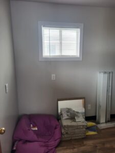 Interior room with rough window opening and electrical outlet, pre-trim stage.