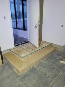 Plywood threshold platform under construction at an exterior door opening, unfinished, taped for protection