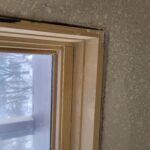 Window casing installed on raw wood jamb, ready for paint; drywall wall unfinished.