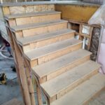 Open-riser garage or patio steps with 2 stringers and raw wood treads mid-construction, no railing installed.