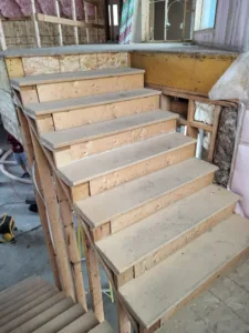Interior stairs during framing with raw OSB treads and exposed wall sheathing nearby