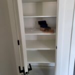 Completed bi-fold closet door with painted white slabs, casing, and black hardware installed.