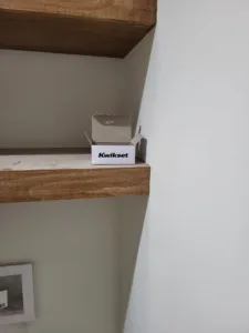 Stained wood floating shelf wrapping an inside corner, with a hardware box staged on top during trim work.