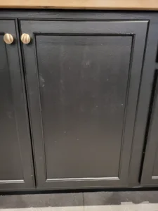 Charcoal painted cabinet doors with panel detail and two round nickel knobs near the top center