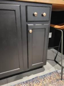Painted cabinet door with recessed panel and brushed gold knob hardware, finished stage