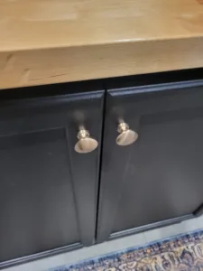 Painted dark cabinet doors with brushed nickel knobs installed beneath a wood countertop