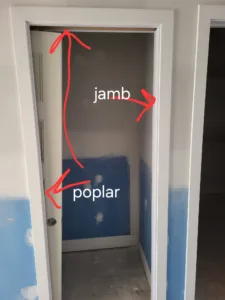 Poplar door jamb inside empty opening, lower walls masked with plastic for painting.