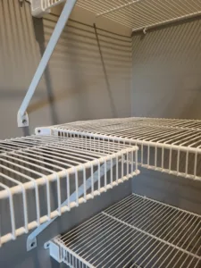 White wire shelving with hanging rod and bracket hooks installed in closet, multiple shelf tiers visible.