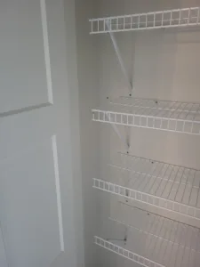 White wire shelving installed in closet with four levels and angled support brackets, door open.