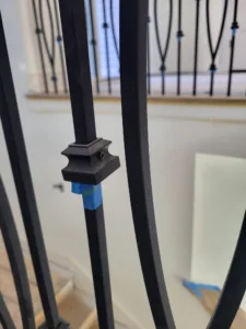 Closeup of decorative scroll pattern iron balusters with a black square post cap