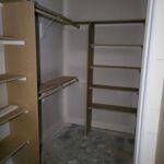 Walk-in closet with multiple shelves and hanging rod installed on wood cleats and brackets, raw wood finish.