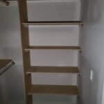 Five-shelf closet unit with particle board shelving and support post, raw wood ready for paint.