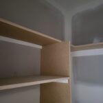 Closet shelf with bullnose edge and particle board backing, raw wood trim not yet painted.