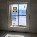 Window casing installed with wood frame and four-pane glass, ready for paint.
