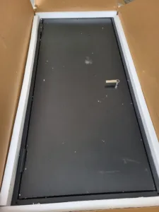 Flat black panel bordered by light-colored trim, laid flat on a plywood subfloor