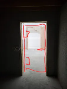 Unfinished door opening with red marker outlining the jamb, framing marked for resizing
