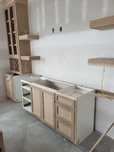Kitchen cabinet boxes installed with open shelving above, in progress before hardware and finish