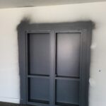 Painted bypass sliding glass doors installed in cased opening with dark frame finish.