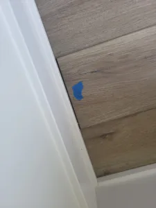 Painted white baseboard installed at a wall-floor junction with wood-look flooring